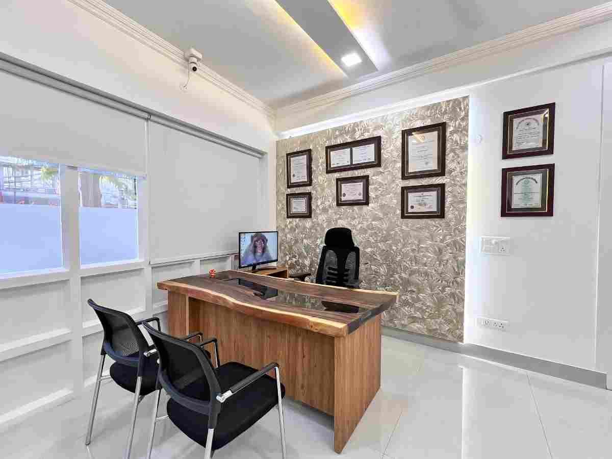 Doctor's consultation office with live-edge wooden desk, framed dental certificates and visitor chairs at Dental World